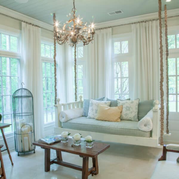 Sunlit living room with elegant drapery, a daybed, and a vintage chandelier creating a tranquil space