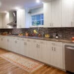 Modern kitchen with stainless steel appliances, white cabinetry, and a mosaic tile backsplash
