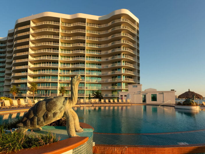 Golden hour at a luxurious condominium complex with a turtle sculpture beside the sparkling pool