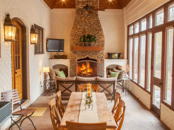 Rustic indoor dining space with a large wooden table, a stone fireplace, and a warm, inviting ambiance