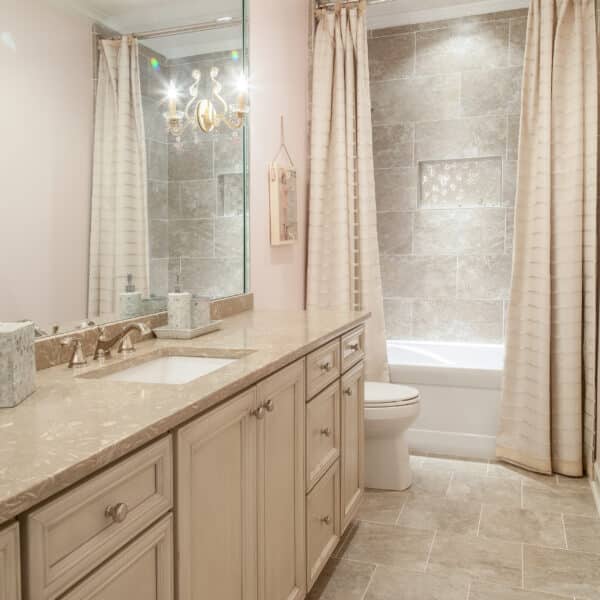 Spacious bathroom with beige cabinetry, tiled walls, a large mirror, and elegant curtain